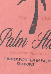 Texte sur tissu rose indiquant "Palm", "Essentiels baignés de soleil" et "Été écrit dans les ombres des palmiers" avec un graphique partiel de palmier.