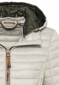 Lysegrå dunjakke med lynlåslukning, der har en mørkegrøn inderforing og brune læderdetaljer på lynlåstrækkeren.