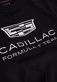 Sort sweatshirt med hvid Cadillac-logo og teksten "Cadillac Formula 1 Team" trykt på forsiden.