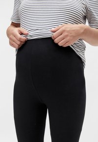 Fekete kismama leggings sima textúrával, magas derékkal és bő nyújthatósággal, csíkos, rövidujjú toppal párosítva.