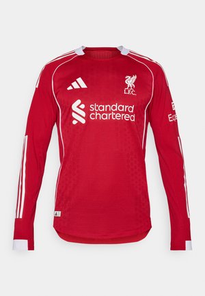 Rotes Langarm-Fußballtrikot mit weißen Akzenten, Rundhalsausschnitt, Netzstruktur, Vereinslogo und Sponsorenbranding auf der Vorderseite.