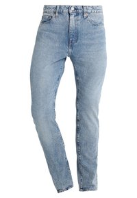 Jeans de mezclilla azul claro con un diseño ajustado, tiro alto y piernas cónicas, con trabillas para cinturón y bolsillos delanteros. Estilo clásico de cinco bolsillos.