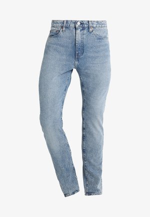 Jeans de mezclilla azul claro con un diseño ajustado, tiro alto y piernas cónicas, con trabillas para cinturón y bolsillos delanteros. Estilo clásico de cinco bolsillos.