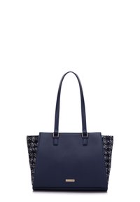 Navy blue tote bag with leather front and textured fabric sides. Features two top handles and a gold logo plate on the front.