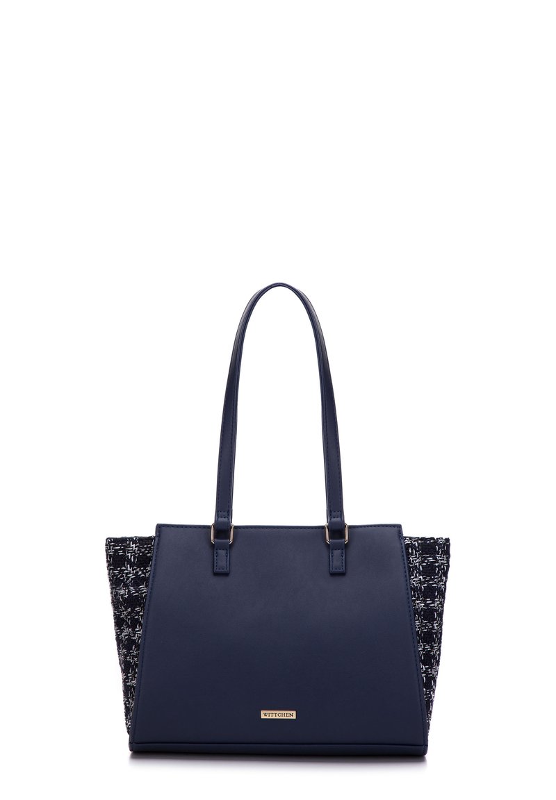Navy blue tote bag with leather front and textured fabric sides. Features two top handles and a gold logo plate on the front.