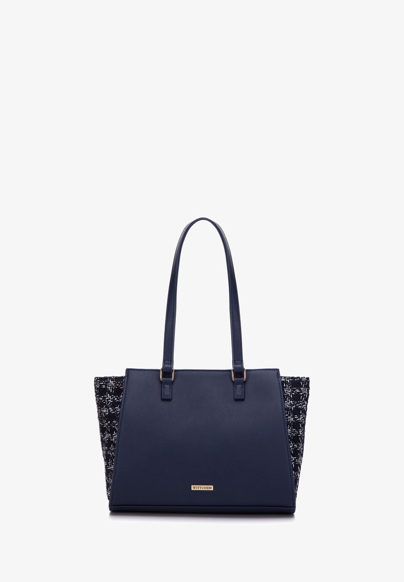 Navy blue tote bag with leather front and textured fabric sides. Features two top handles and a gold logo plate on the front.