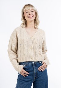 Beige színű, kötött kardiogán, V nyakkal, arany gombokkal és virágos hímzéssel a vállakon. Bordás szegély és hosszú ujjú.