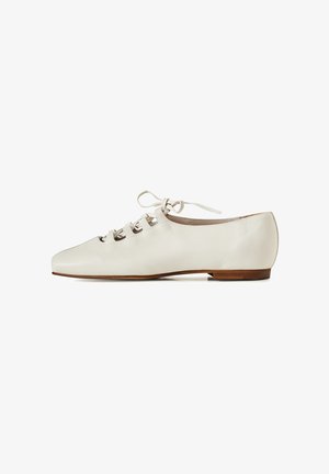 Witte leren platte schoen met vierkante neus, veters aan de voorkant en lage houten hak, zijaanzicht op een witte achtergrond.