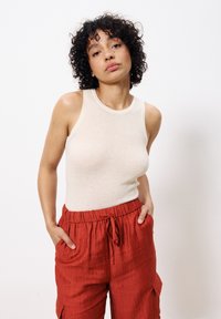 Crème ribbed tanktop met een ronde halslijn, gecombineerd met loszittende rode textuur broek met een elastische tailleband en zakken.