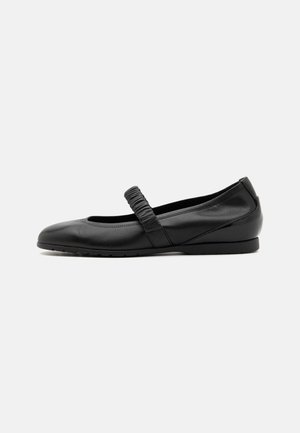 Ballerines en cuir noir avec un bout arrondi et une sangle plissée sur le cou-de-pied. Dotées d'une semelle plate avec traction. Texture lisse.