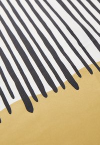 Schwarz-weißer Streifenstoff mit einem tropfenförmigen Design, das am unteren Rand in eine einheitliche senfgelbe Farbe übergeht. Glatte Textur.