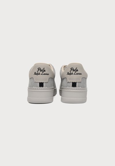 Ζευγάρι γκρι αθλητικά παπούτσια Polo Ralph Lauren, εμφανιζόμενα από πίσω με μπεζ ταμπέλες στη φτέρνα και μαύρη ριγέ λεπτομέρεια πάνω από τις σόλες.