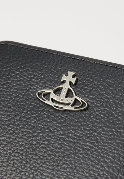 Black textured leather product featuring a metallic silver emblem of a crown and rings, with intricate detailing and polished finish.