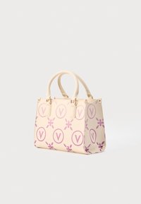 Beige tote bag with purple floral and logo pattern, double handles, textured surface, and gold-tone hardware accents. Compact rectangular shape.