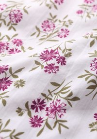 Vitt tyg med ett blommönster som har rosa blommor och gröna blad. Texturen verkar mjuk och lätt.