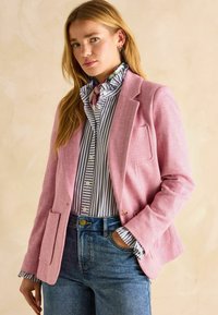 Roosa herringbone-musteriga bleiser, millel on üks tasku, kantud sinise ja valge triibulise särgi peal, millel on volangiga krae, koos kõrge vöökohaga teksadega.