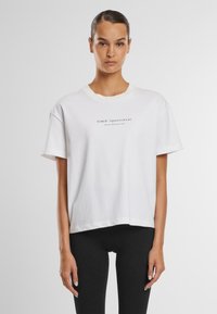 Balta medvilninė trumpa T marškinėliai su apvaliu iškirpimu ir trumpomis rankovėmis, centre spausdintas juodas "AIM'N Sportswear" tekstas.