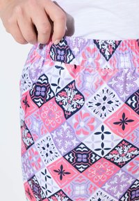 Bunt gemusteter Stoff mit einem Diamantdesign in Pink, Lila und Marineblau. Sichtbarer elastischer Bund, weiche Textur, leichtes Material.