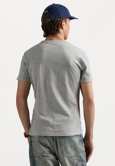 Tricou din bumbac gri, cu mâneci scurte, având un guler rotund. Purtați-l cu blugi albaștri decolorati și o șapcă bleumarin. Textură netedă, croială lejeră.