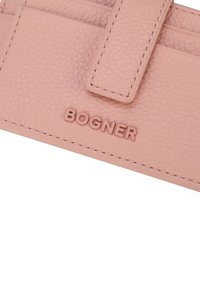 Portafoglio in pelle texturizzata rosa con logo in rilievo tono su tono. Presenta una chiusura sicura e cuciture precise. Forma compatta e rettangolare.