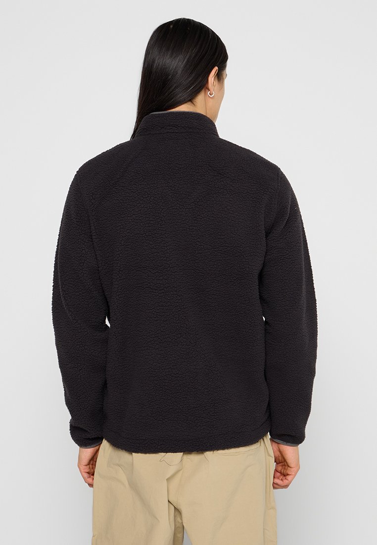 Giacca in pile nera con superficie testurizzata e colletto alto. Caratterizzata da maniche lunghe e orlo dritto in vita.