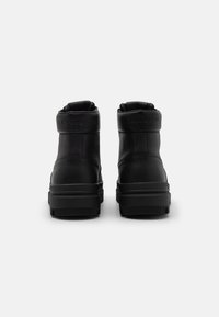 Stivaletti in pelle nera con finitura testurizzata, dotati di colletto imbottito e suola in gomma piatta. Logo del marchio impresso sul retro.