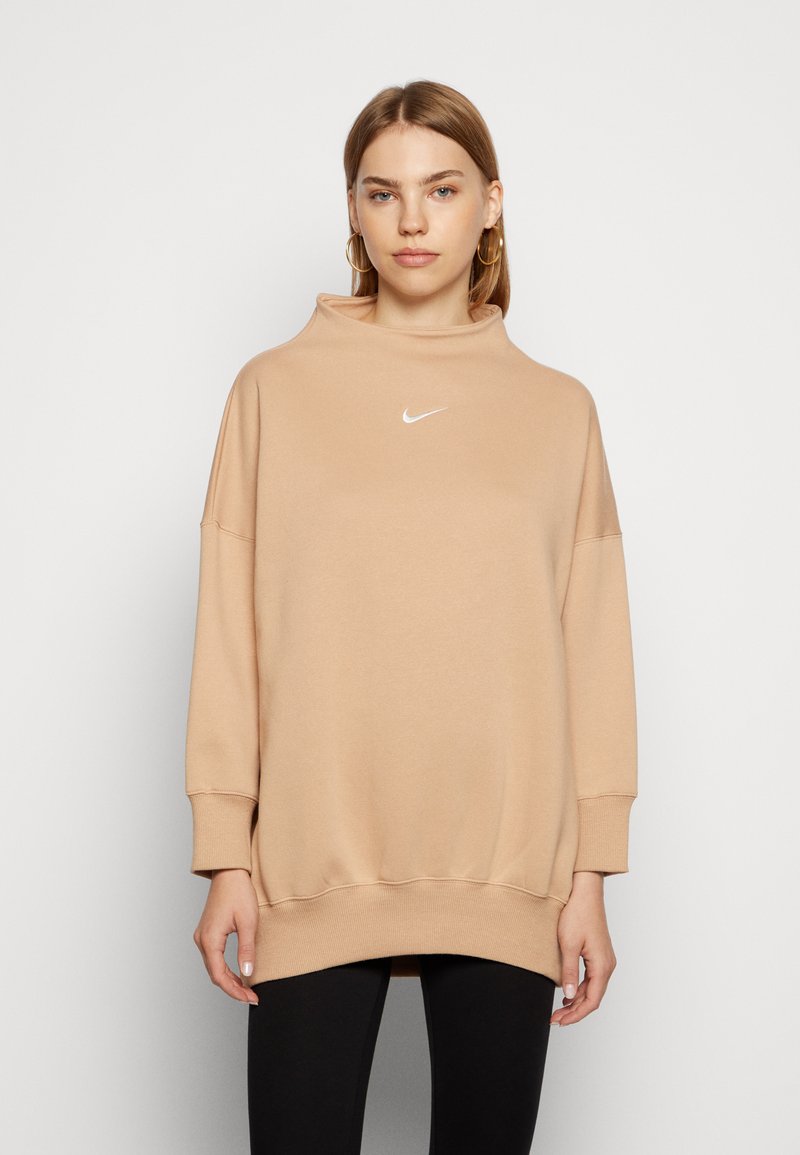 Felpa beige over-size con collo alto, maniche lunghe e logo Nike bianco sul petto, realizzata in tessuto morbido e liscio.