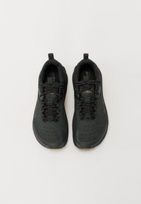Czarne buty biegowe z teksturowaną cholewką, sznurówką i pętlą. Posiadają gumową podeszwę z żółtym akcentem i subtelnym logo.