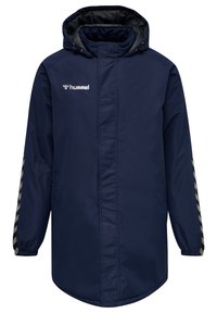 Marinblå lång kappa, vattentåligt material, har en huva, dragkedjestängning och randig detalj på ärmarna; logotyp på bröstet.