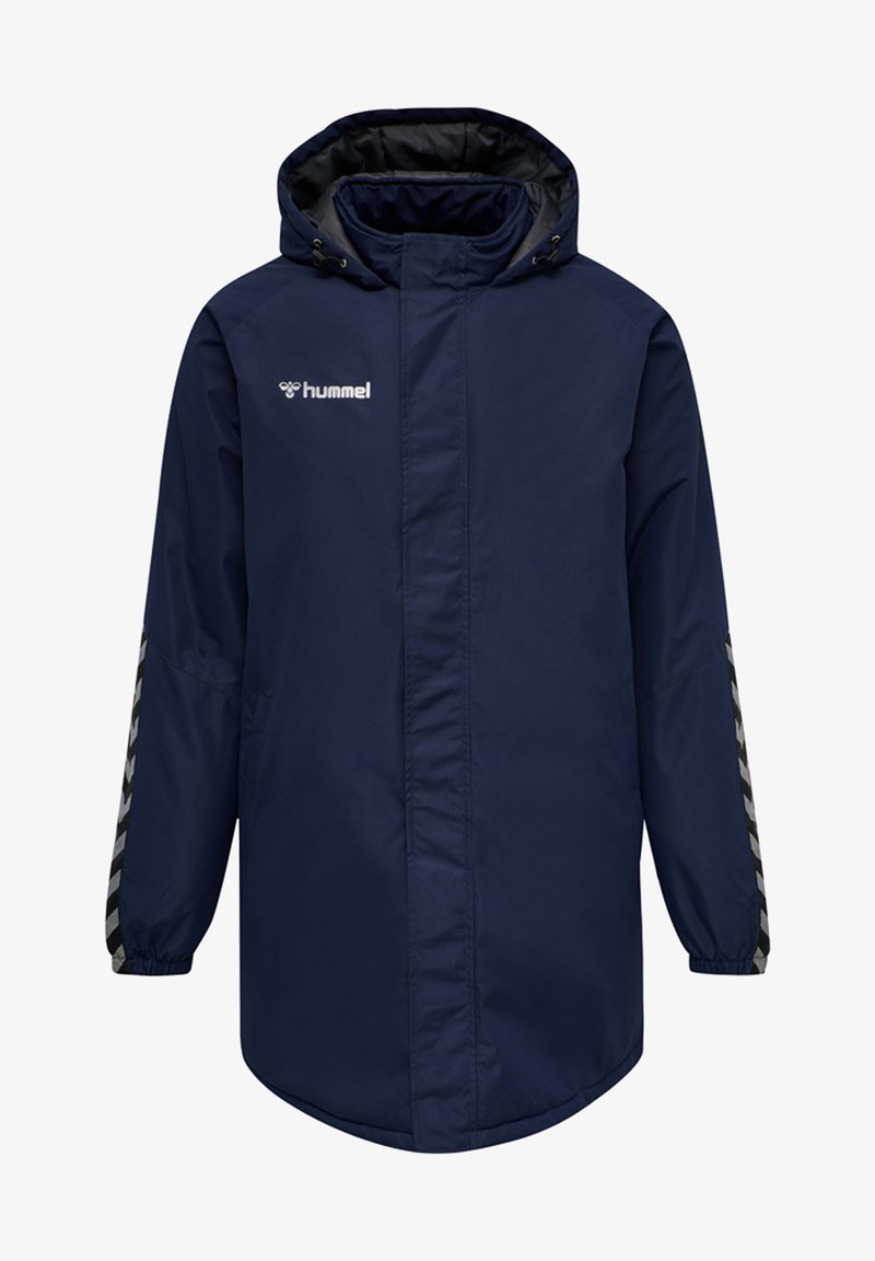 Marinblå lång kappa, vattentåligt material, har en huva, dragkedjestängning och randig detalj på ärmarna; logotyp på bröstet.