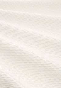 Tessuto bianco testurizzato con un sottile motivo a onde, che crea una superficie liscia ma in rilievo, ideale per diverse applicazioni tessili.