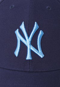 Casquette bleu marine en tissu avec un logo "NY" brodé en bleu clair. La casquette a une forme structurée et comprend un détail de couture.