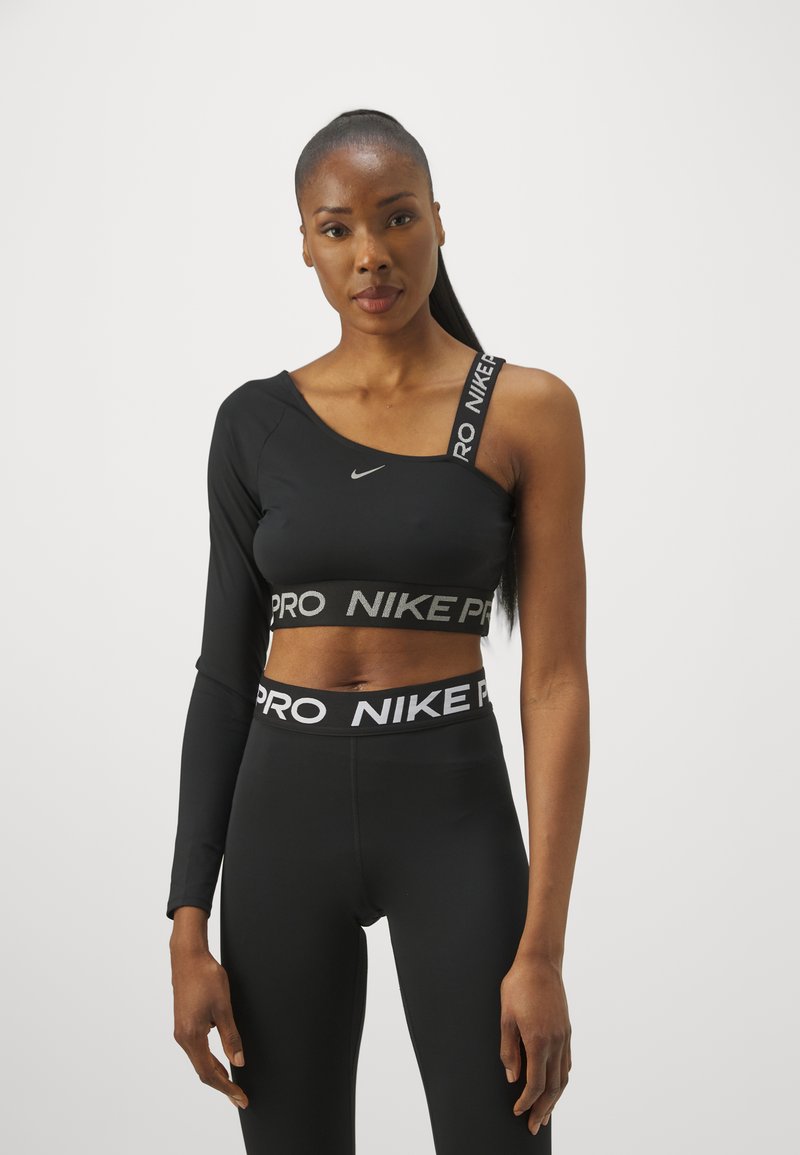 Svart treningscrop-top med én lang erme, med Nike-logo og "NIKE PRO"-bånd. Båret med matchende høyt liv leggings.