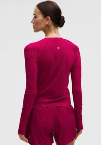 Fitte langemouwen overhemd in levendig fuchsia, gemaakt van zacht, gestructureerd materiaal. Heeft contrasterende stiksels en een logo op de achterkant.