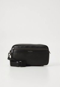Borsa a tracolla in pelle nera con texture liscia, forma rettangolare, chiusura superiore con cerniera e tracolla regolabile. Logo Calvin Klein impresso.