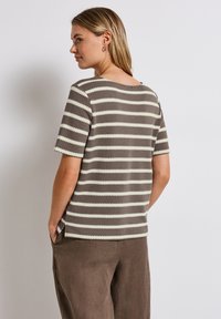 Šedá a krémová pruhovaná polokošile s texturovaným povrchem a kulatým výstřihem, zkombinovaná s volnými hnědými kalhotami.