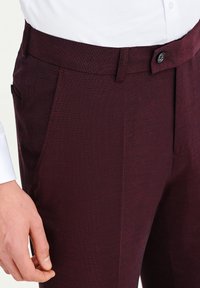 Burgundowe spodnie dopasowane wykonane z fakturowanej tkaniny, z pojedynczym zapięciem na guzik, bocznymi kieszeniami i eleganckim, prostym krojem.