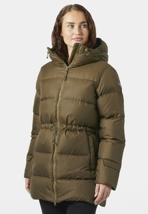 Vrouw met een olijfgroene gewatteerde winterjas met capuchon, rits aan de voorkant en taillekoord, kijkt opzij tegen een neutrale achtergrond.