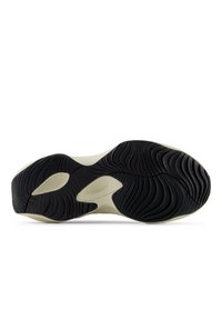 Sålen på en sneaker med ett vågigt texturerat svart mönster på undersidan, med en slät krämfärgad sektion runt kanterna.