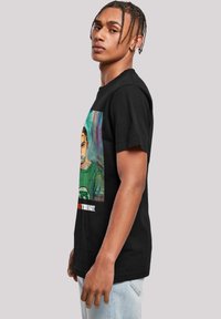 Camiseta de algodón negra con un colorido estampado gráfico de una persona con un top verde, con el texto "TUBOYZ" en la parte inferior. Corte clásico.