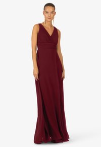 Bordowa suknia maxi z dekoltem w kształcie litery V i plisowanym bokiem, z lekko opadającą spódnicą, tworzącą elegancką sylwetkę. Miękka tekstura materiału.