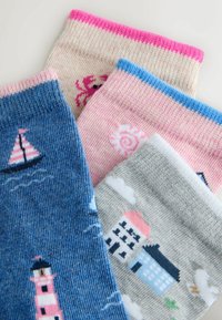 Quatre chaussettes enfantines colorées avec des motifs nautiques et marins comprenant un voilier, un phare, un crabe, un soleil, des maisons, des nuages et un oiseau.