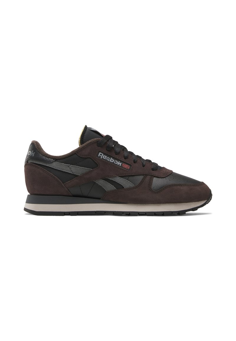 Die Reebok-Sneaker besitzen ein Obermaterial aus dunkelbraunem Wildleder und schwarzem Leder, mit einem grauen Logo und Akzenten sowie einer hellgrauen Sohle. Niedrigschnitt-Design.