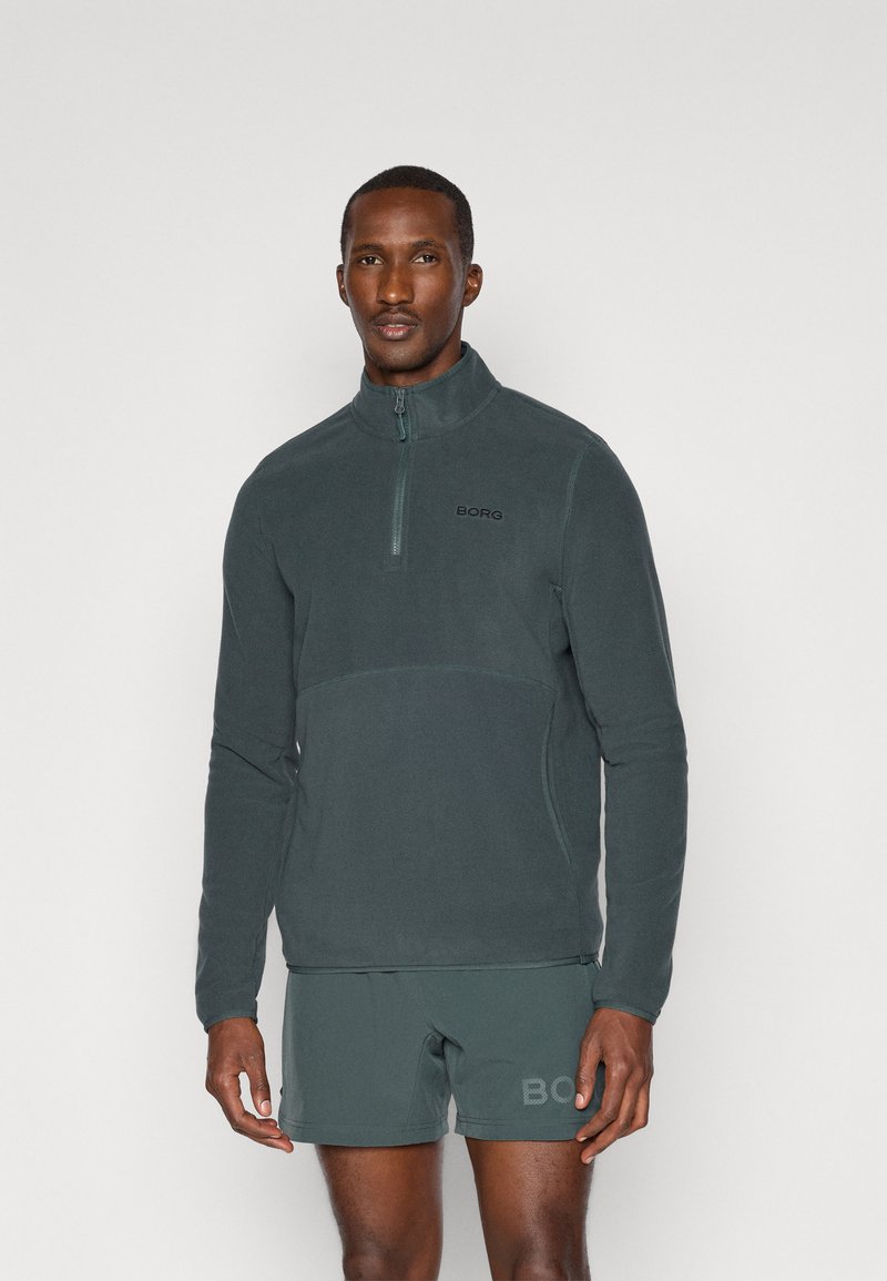 Pullover in pile grigio scuro con colletto a mezza zip, caratterizzato da un design semplice, una texture liscia e un logo discreto sul petto.