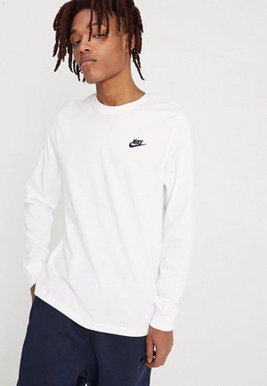 White long-sleeve T-shirt made of cotton, featuring a small black Nike logo on the left chest and a crew neck design.
