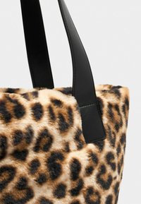 Tote bag met luipaardprint en kunstbontstructuur, voorzien van zwarte leren banden en een gestructureerde vorm, die een levendig patroon benadrukt.