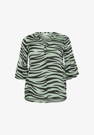 Mustard ja mündi rohelise zebra mustriga pluus V-kaelusega, nööpide aktsent ja 3/4 kellukese varrukad, mis on valmistatud kergest kangast.