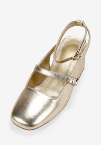 Zapato de tacón cuña metálico dorado con punta cuadrada, tira ajustable tipo slingback y una delgada tira decorativa a lo largo del arco. Textura suave.