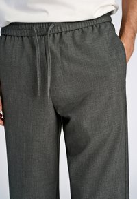 Grijze textuurbroek met elastische tailleband met trekkoord, zijzakken en een rechtgesneden pijp.