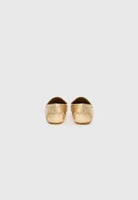 Gold leather slip-on shoes with a smooth texture, rounded toe, and low profile. Simple design with no visible hardware or patterns.